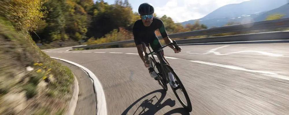 Cycliste en descente dans un virage sur un vélo de route, sur une route de montagne
